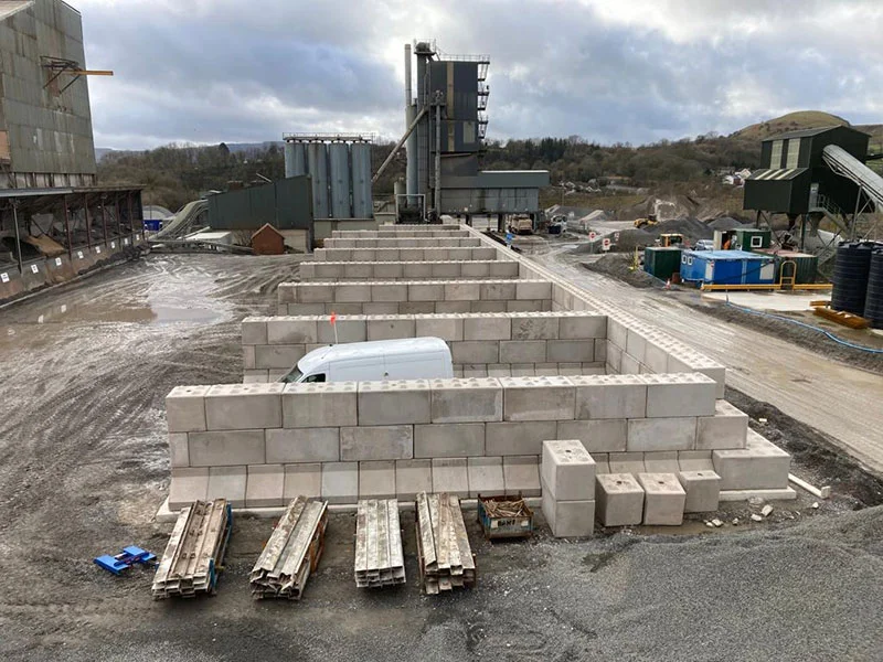 Legato block storage bays part-built beside an asphalt plant with a van parked inside
