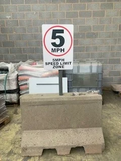 Precast concrete block base holding a 5 mph speed limit sign post