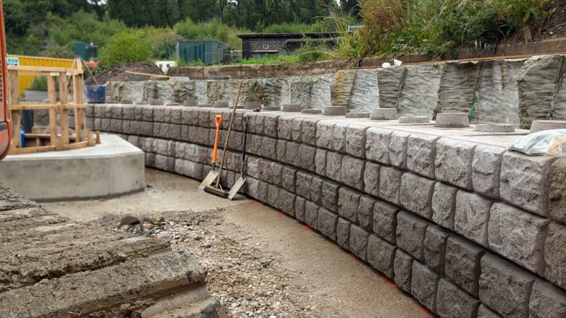 Cobblestone-finish Retainer-Rock walls curving around a treatment works excavation
