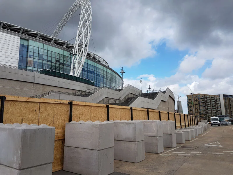 Kentledge blocks anchoring a run of timber hoarding outside a stadium