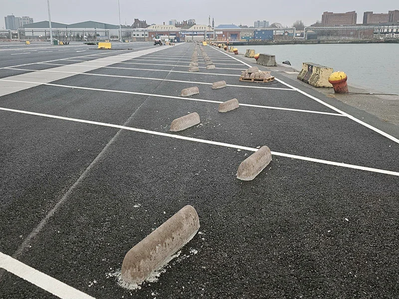 Concrete wheel stops laid out across marked lorry parking bays at a port