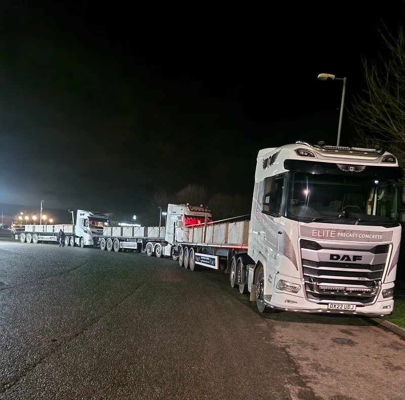 Lorries with flatbed trailers lined up for block deliveries to site at night