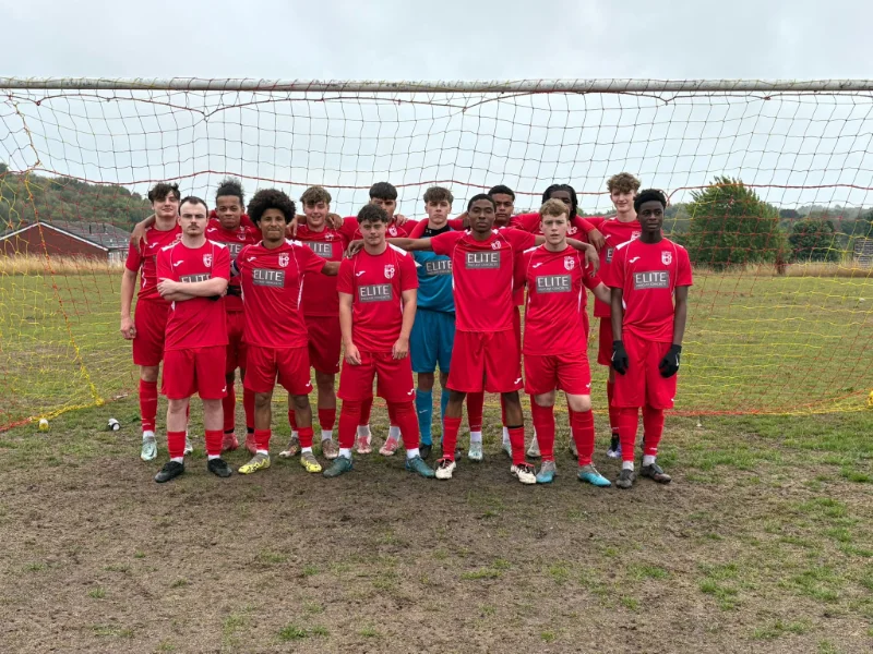 Youth football team in red kit lined up in front of a goal