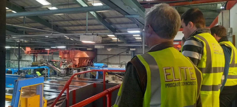 Visitors in hi-vis vests touring a concrete production line inside the factory