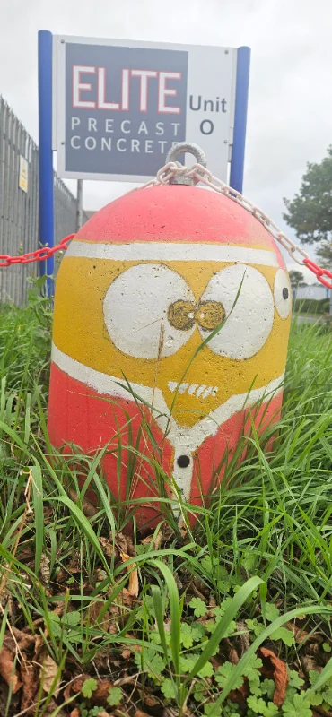 Red and yellow Minion-Bollard painted with a face, chained beside a unit entrance sign